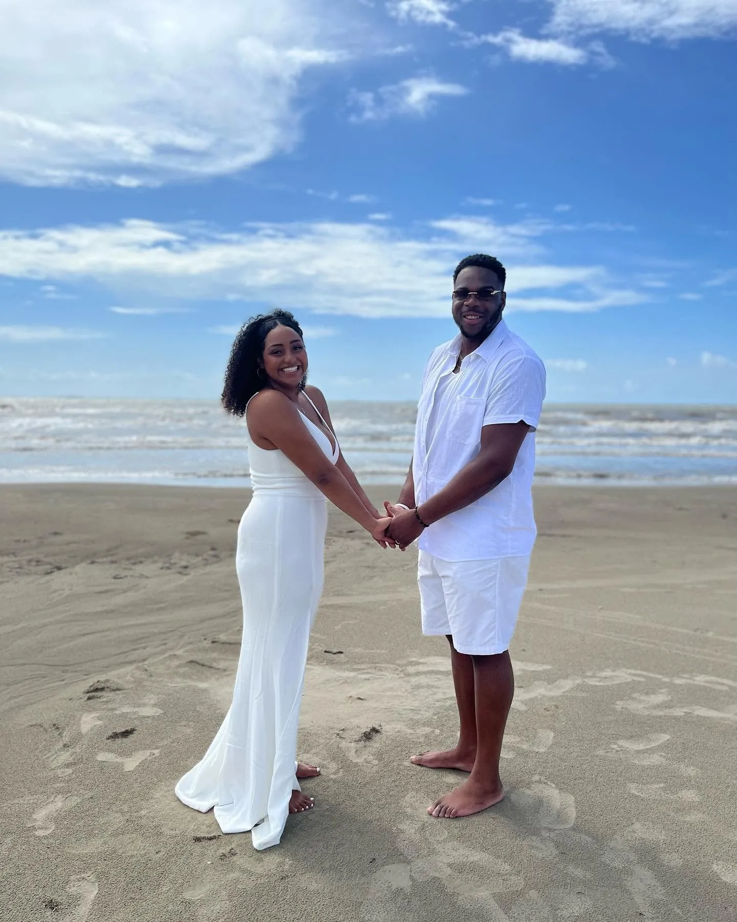 Newlywed couple holding hands barefoot on a Texas beach